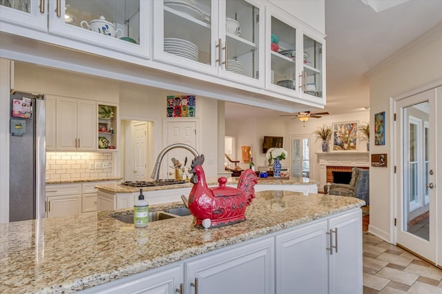 kitchen featuring white cabinets, light stone counters, freestanding refrigerator, and decorative backsplash