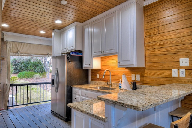 kitchen featuring wooden ceiling, stainless steel fridge, white cabinetry, and a sink