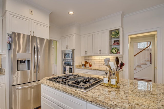 kitchen featuring appliances with stainless steel finishes, white cabinets, crown molding, and backsplash