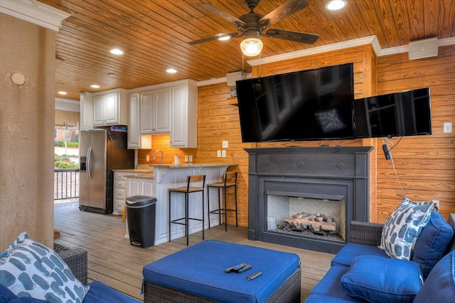 living room with a fireplace, recessed lighting, wooden walls, light wood-type flooring, and wooden ceiling