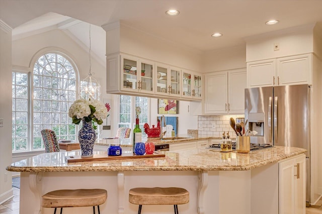 kitchen with white cabinets, backsplash, glass insert cabinets, and a healthy amount of sunlight