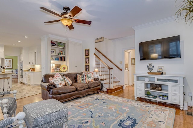 living area featuring ceiling fan, recessed lighting, stairway, light wood-type flooring, and crown molding