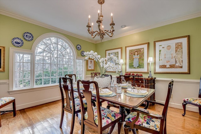 dining area featuring light wood-style floors, crown molding, baseboards, and an inviting chandelier