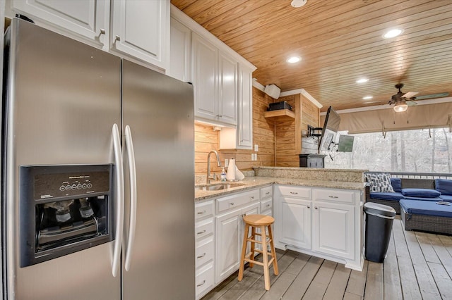 kitchen featuring wood ceiling, white cabinets, stainless steel fridge, and a sink