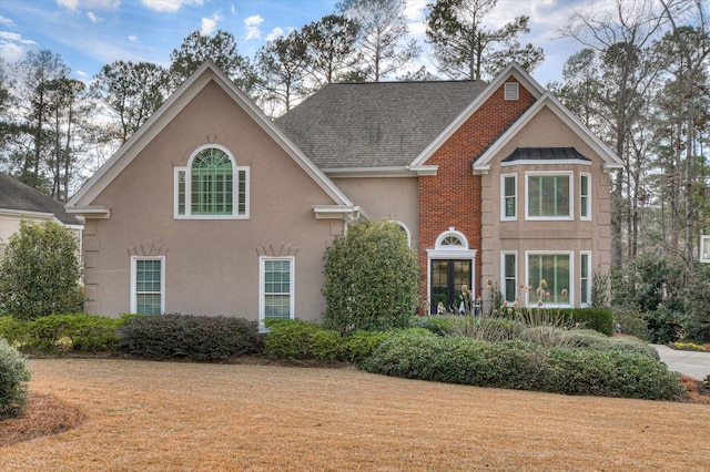 traditional-style home featuring roof with shingles and stucco siding