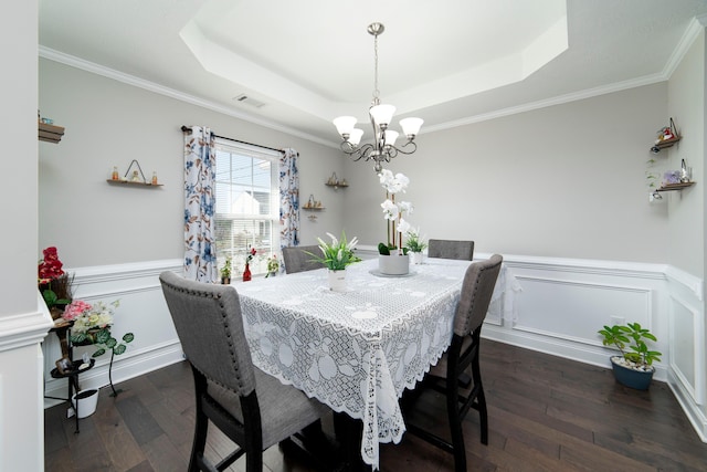 dining room featuring an inviting chandelier, a tray ceiling, crown molding, and dark wood-type flooring