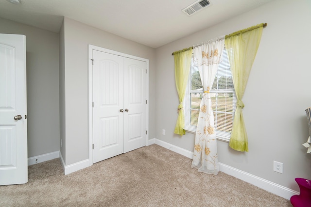 unfurnished bedroom featuring light carpet and a closet