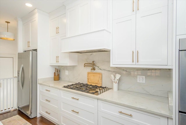 kitchen with white cabinets, fridge with ice dispenser, premium range hood, stainless steel gas stovetop, and backsplash