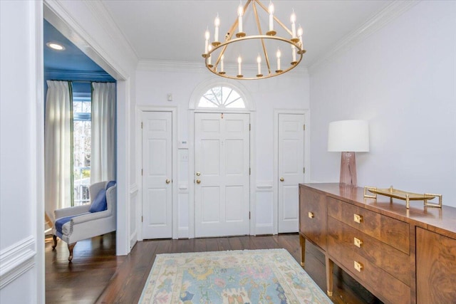 entrance foyer with ornamental molding, dark wood finished floors, a wealth of natural light, and an inviting chandelier