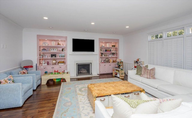 living area with built in shelves, dark wood finished floors, recessed lighting, a fireplace with raised hearth, and ornamental molding