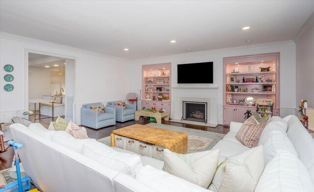 living area with ornamental molding, a fireplace, wood finished floors, and built in features