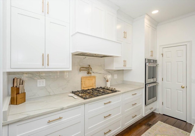 kitchen featuring backsplash, appliances with stainless steel finishes, dark wood-type flooring, white cabinetry, and light stone countertops