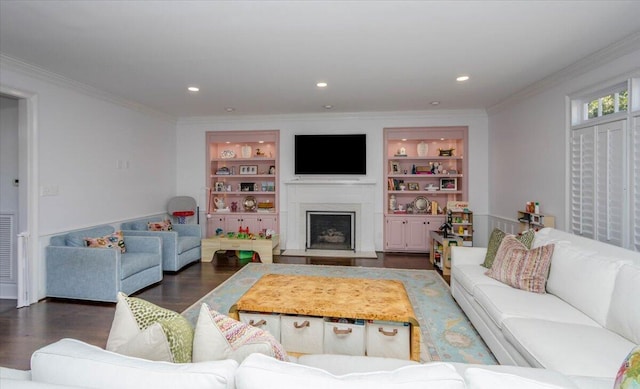 living room with a fireplace with raised hearth, ornamental molding, wood finished floors, and built in features