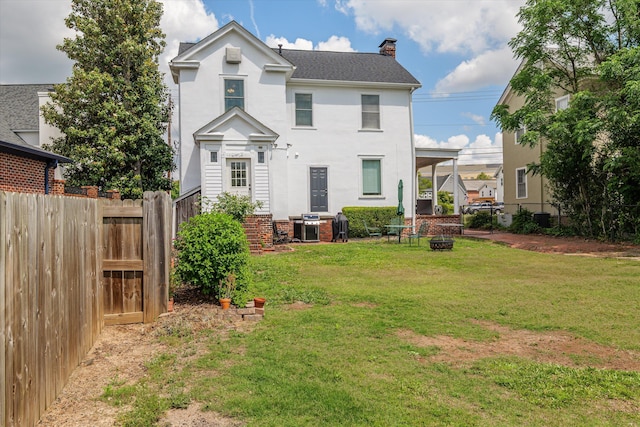 rear view of property with an outdoor fire pit, fence, a yard, and a chimney