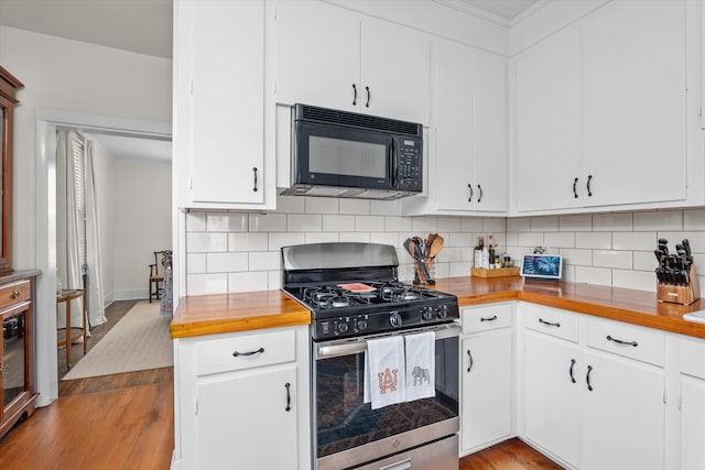 kitchen with stainless steel gas range, black microwave, light wood-style flooring, tasteful backsplash, and butcher block counters