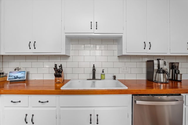 kitchen featuring stainless steel dishwasher, backsplash, white cabinets, and a sink