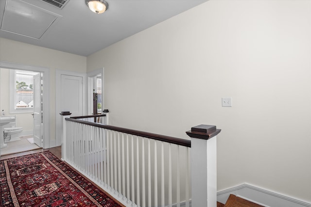 hallway featuring baseboards, visible vents, attic access, and an upstairs landing