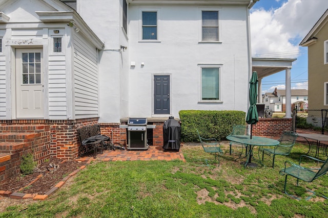 rear view of property featuring a lawn, fence, and stucco siding