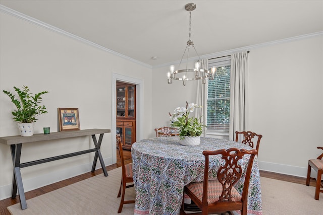dining room featuring baseboards, ornamental molding, light wood finished floors, and a notable chandelier