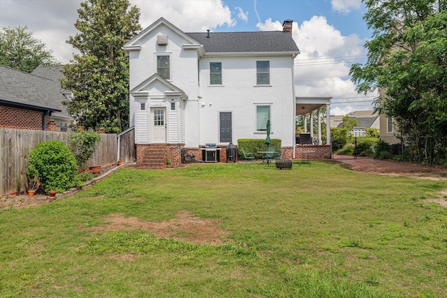 rear view of property featuring a lawn, a chimney, and a fenced backyard