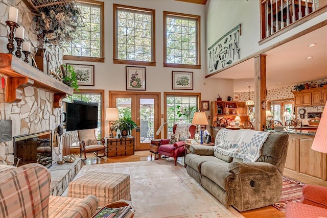 living room with french doors, plenty of natural light, a fireplace, and a high ceiling