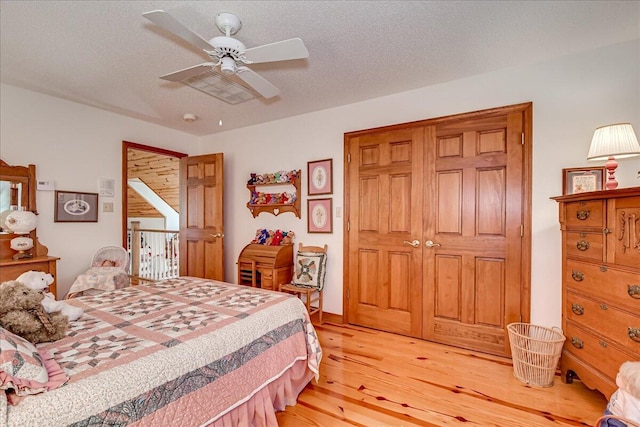 bedroom featuring ceiling fan, light hardwood / wood-style floors, a textured ceiling, and a closet