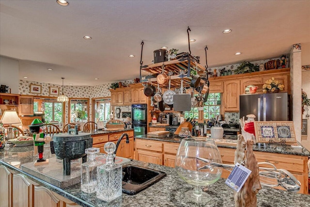 kitchen with double oven, stainless steel refrigerator, sink, and pendant lighting