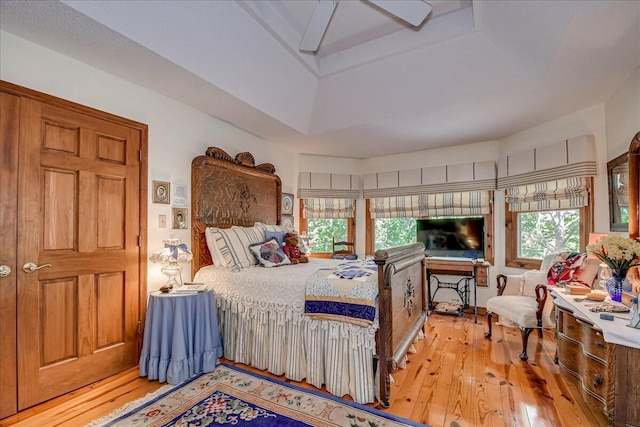 bedroom with hardwood / wood-style floors, ceiling fan, and a tray ceiling