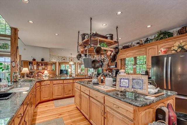 kitchen with kitchen peninsula, a wealth of natural light, light hardwood / wood-style floors, and fridge