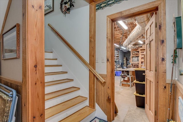 stairway with concrete flooring and wood walls