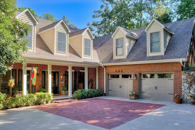 cape cod house featuring covered porch and a garage