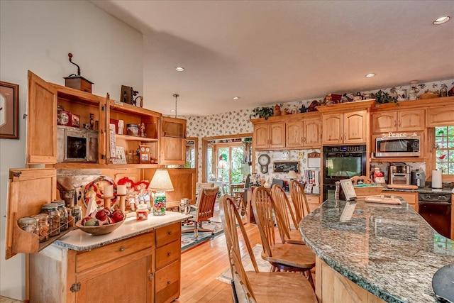 kitchen featuring double oven, dark stone countertops, light hardwood / wood-style floors, and decorative light fixtures