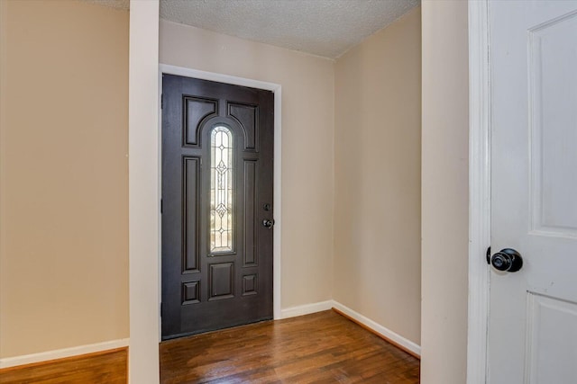 foyer featuring baseboards, a textured ceiling, and dark wood finished floors