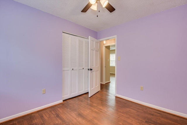 unfurnished bedroom featuring wood finished floors, baseboards, a closet, and a textured ceiling