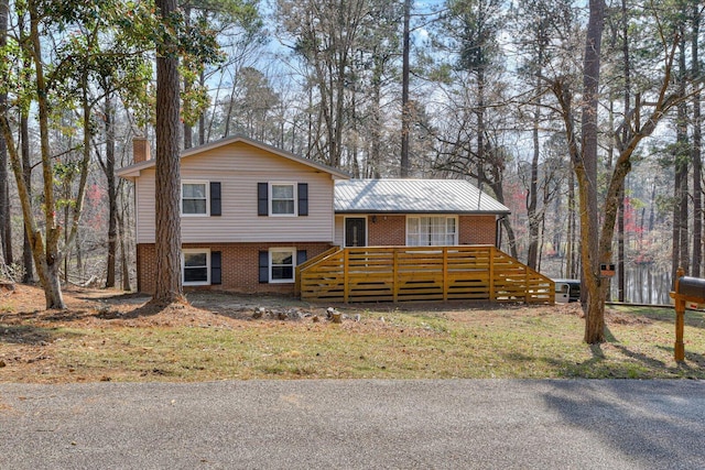 tri-level home with a wooden deck, brick siding, and a chimney