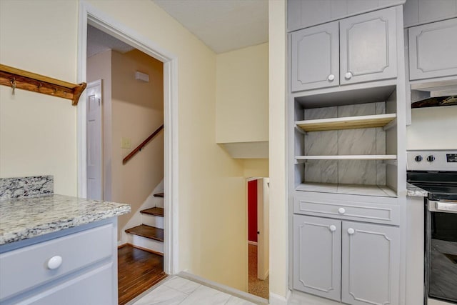 kitchen featuring open shelves, electric range, and baseboards