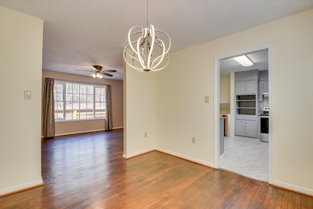 unfurnished room with baseboards, a textured ceiling, light wood-style flooring, and ceiling fan with notable chandelier