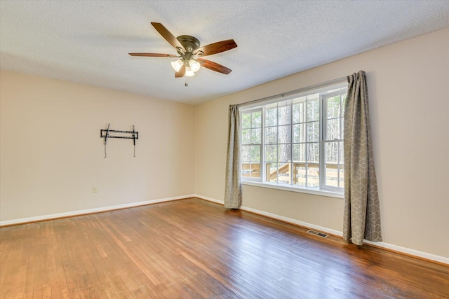 spare room featuring a textured ceiling, wood finished floors, visible vents, and ceiling fan