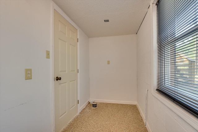 corridor with a textured ceiling and baseboards