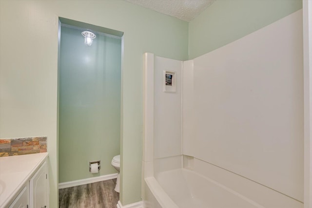 full bathroom with vanity, wood finished floors, baseboards, a textured ceiling, and toilet