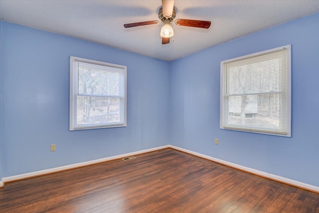 unfurnished room with baseboards, visible vents, wood-type flooring, and a healthy amount of sunlight