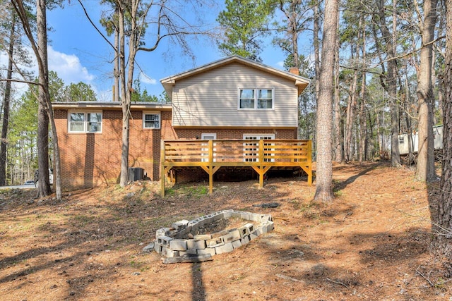 back of property featuring brick siding, an outdoor fire pit, and a deck