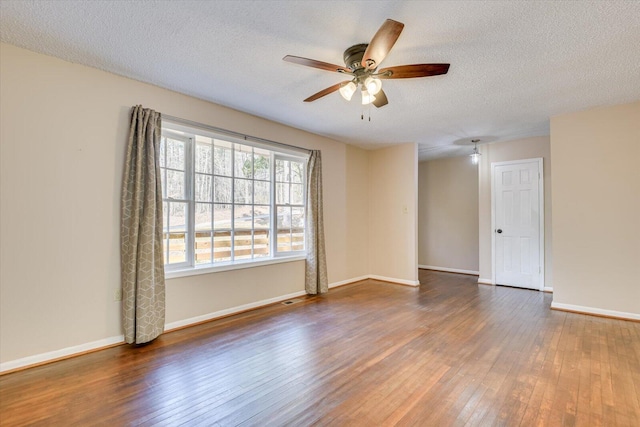 empty room with visible vents, hardwood / wood-style flooring, a textured ceiling, baseboards, and ceiling fan