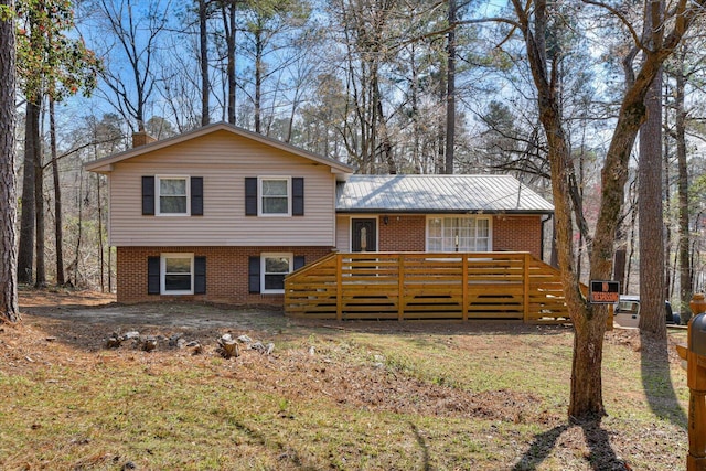 tri-level home with brick siding, a chimney, a front lawn, and a deck