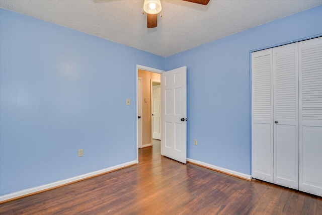 unfurnished bedroom featuring wood finished floors, baseboards, ceiling fan, a closet, and a textured ceiling