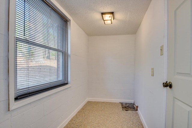 unfurnished room with a textured ceiling and concrete block wall