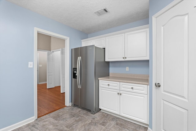 4046 Stone Pass Dr, Graniteville, SC 29829 - kitchen with stainless steel fridge with ice dispenser, white cabinets, light countertops, and a textured ceiling