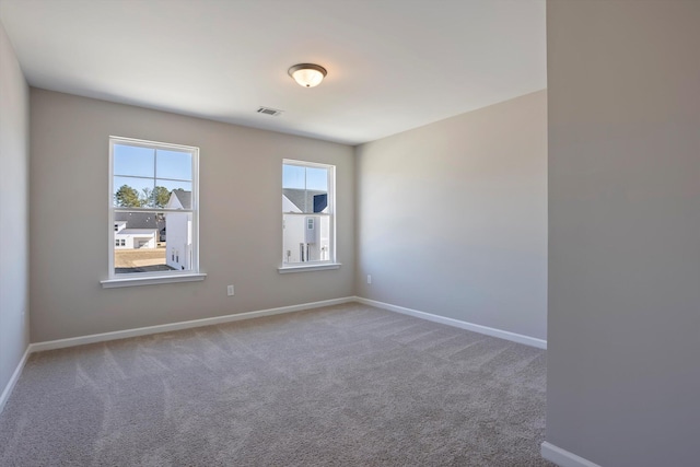 carpeted spare room featuring visible vents and baseboards