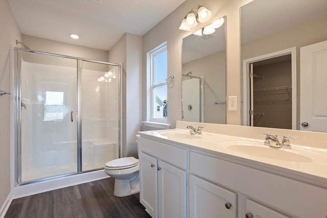 bathroom featuring toilet, a stall shower, a sink, and wood finished floors