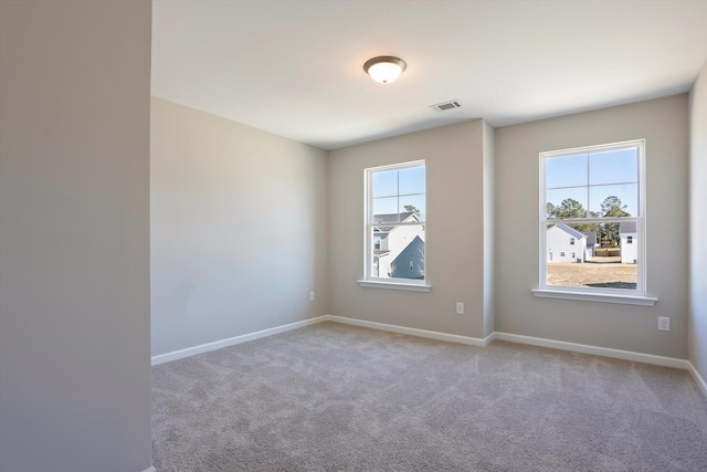 unfurnished room featuring carpet, visible vents, and baseboards